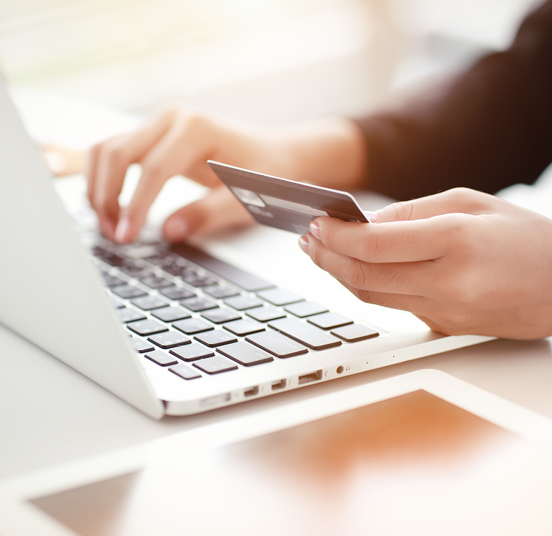 Person holding a credit card while using a laptop, representing CareCredit financing for dermatology procedures.