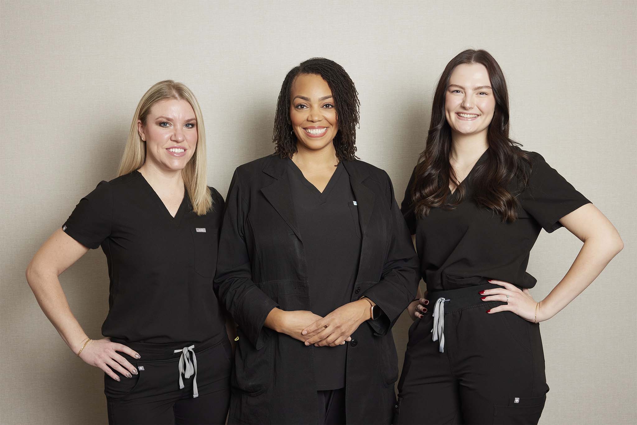 Cosmetic staff at Grosse Pointe Dermatology & Cosmetic Center, three smiling team members in black uniforms.