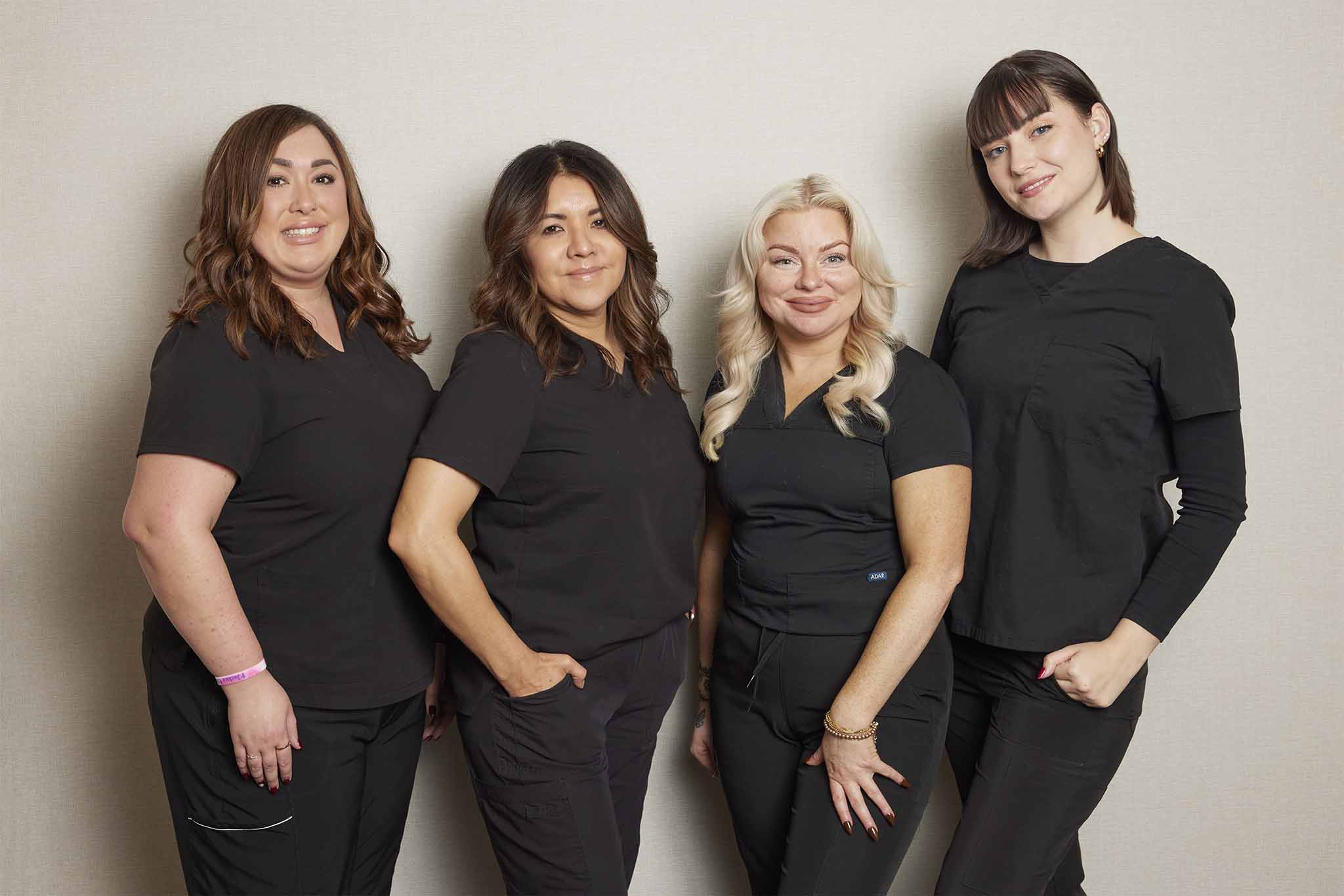 Front office staff at Grosse Pointe Dermatology & Cosmetic Center, four smiling team members in black uniforms.