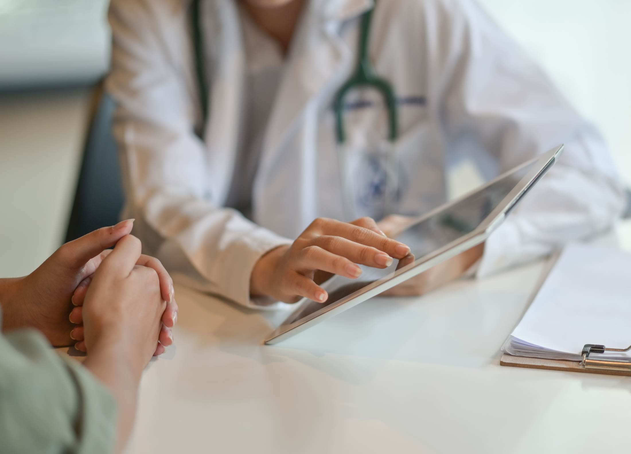 Dermatologist consulting a patient at Grosse Pointe Dermatology & Cosmetic Center, pointing to a digital tablet to explain treatment options. 