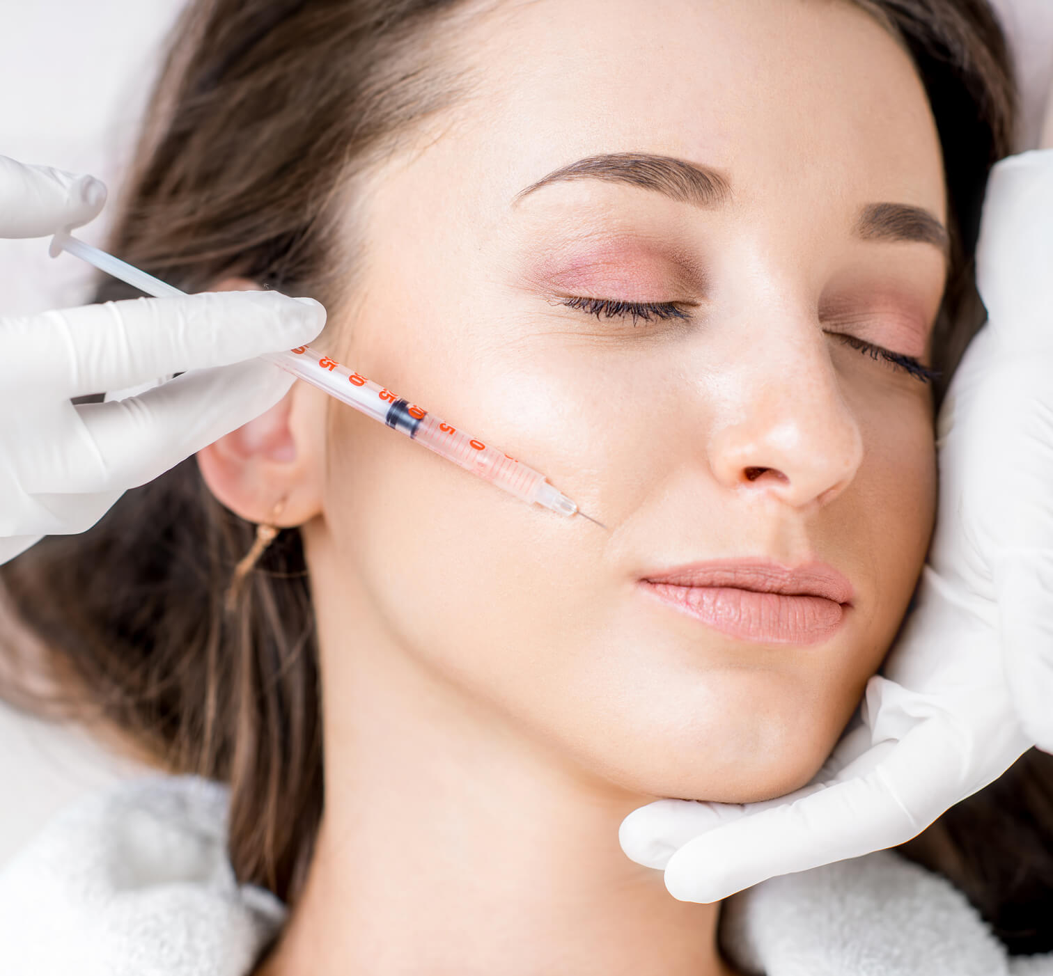 Dermatologist administering a Botox injection near the jawline to treat bruxism.