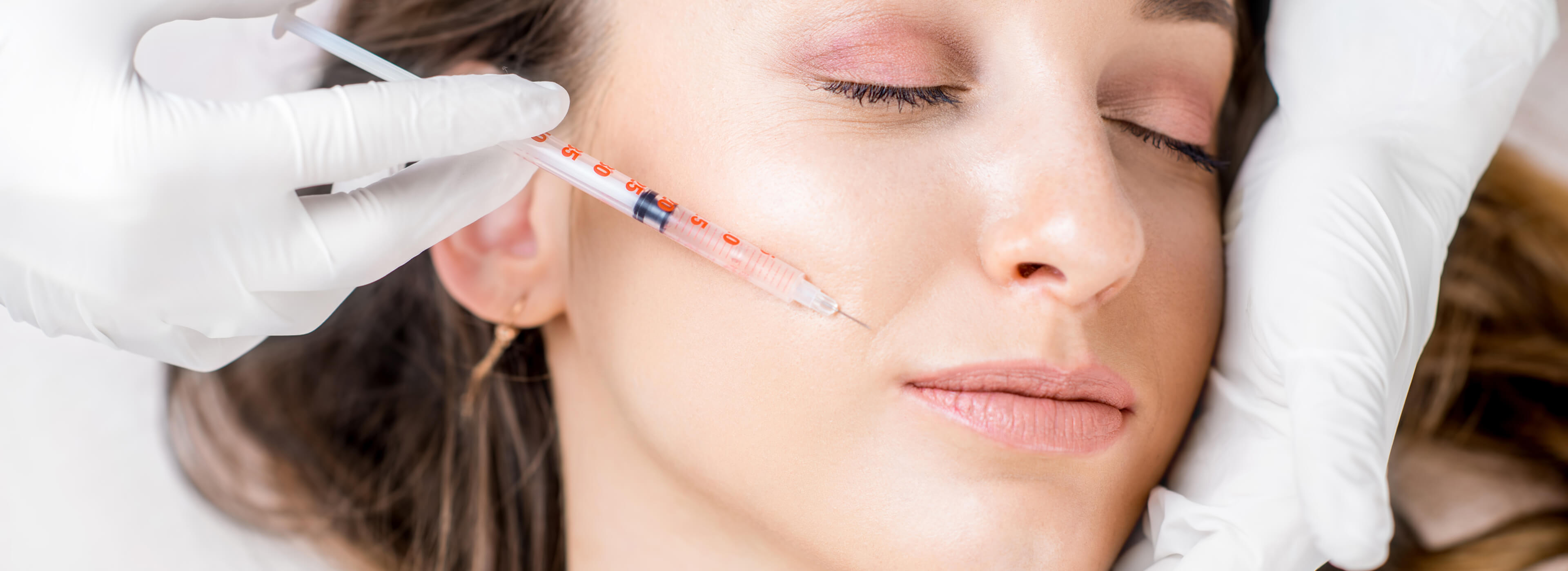 Dermatologist administering a Botox injection near the jawline to treat bruxism.