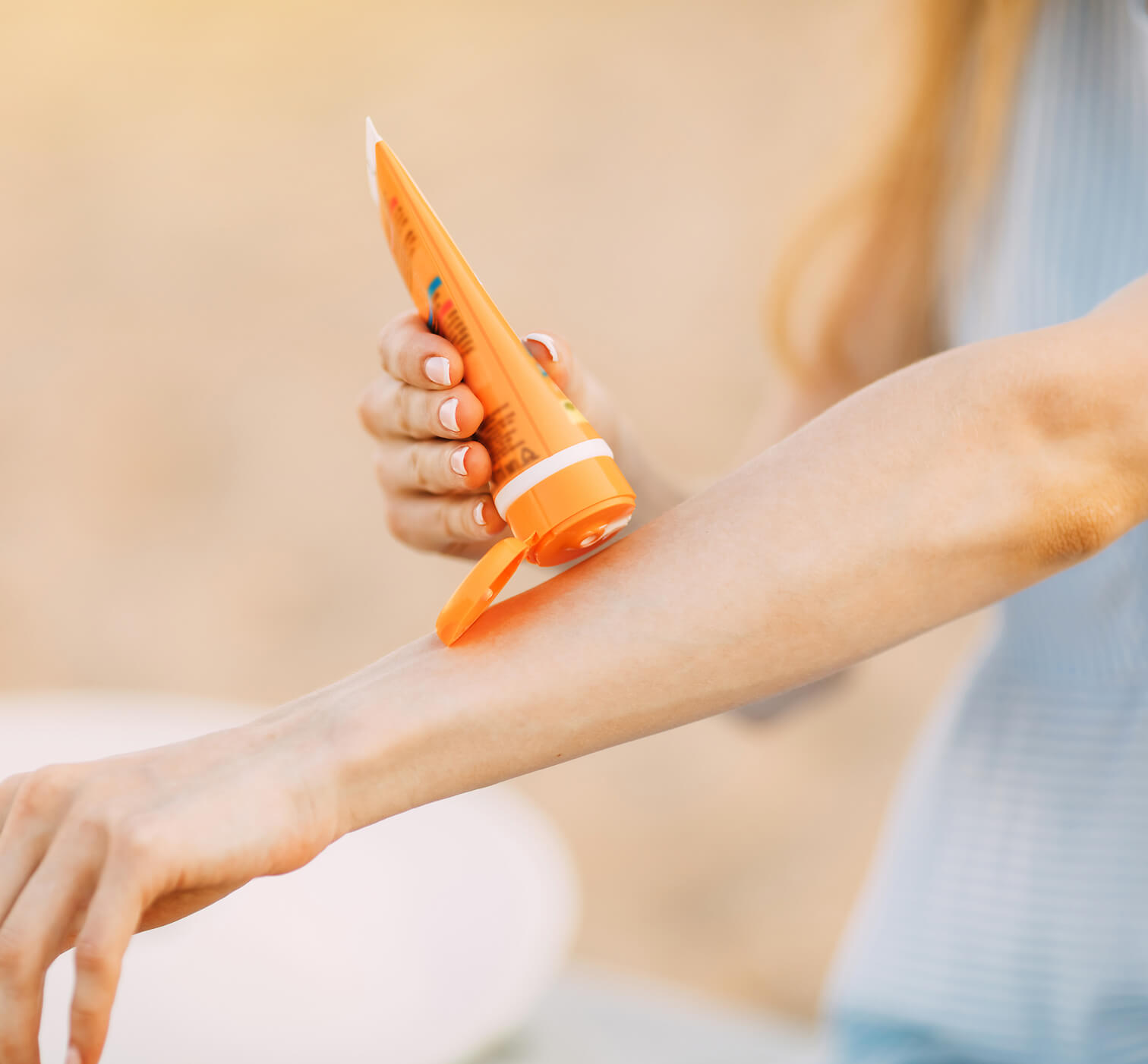 Person applying sunscreen outdoors as part of daily sun protection.